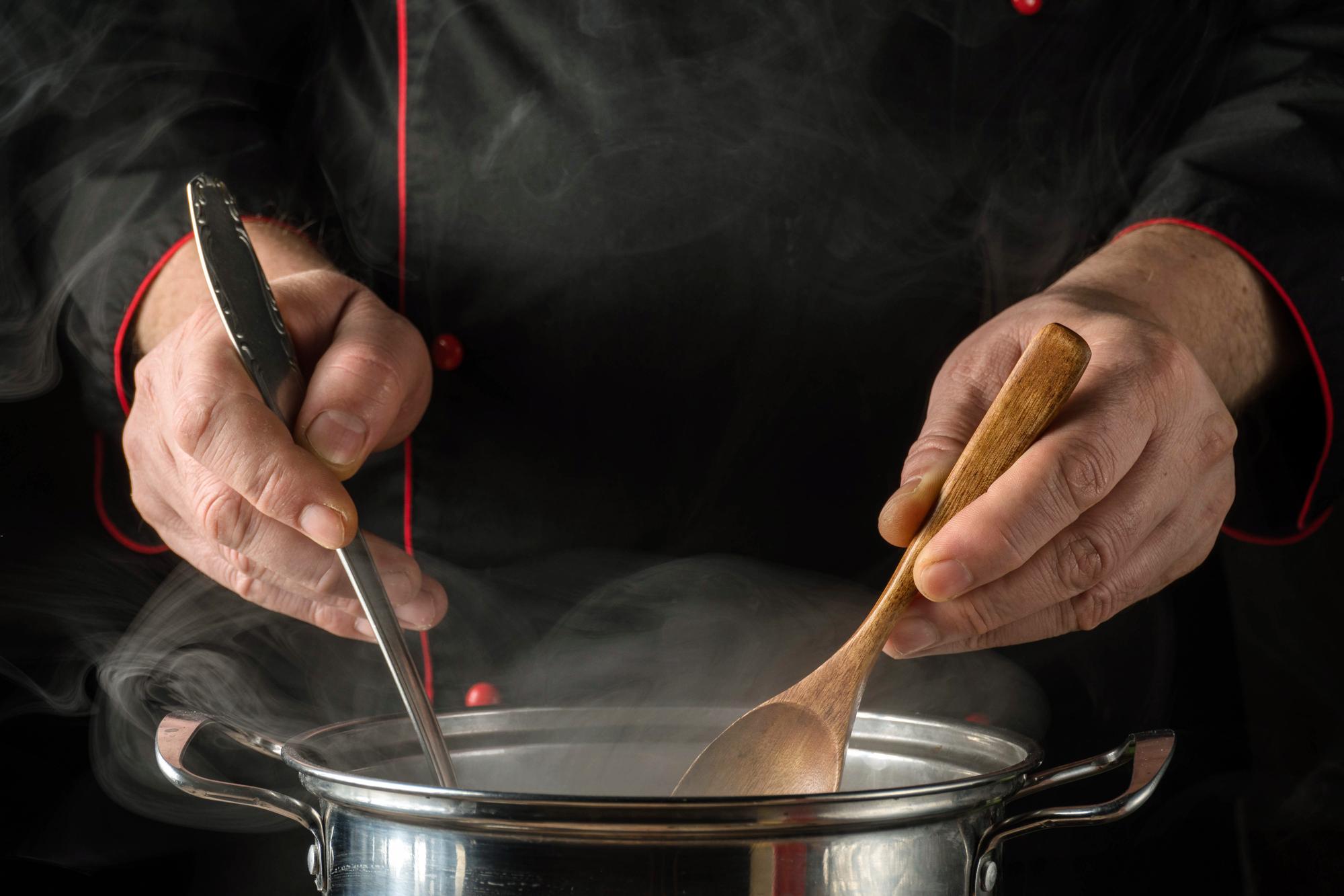 Chef's hands finishing a sauce on a plate