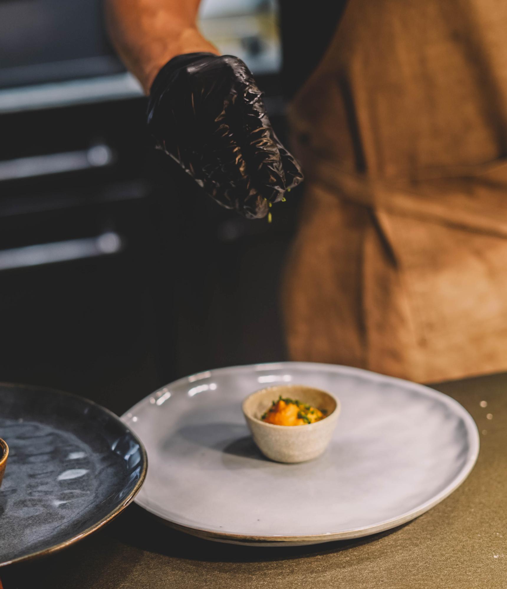 Chef plating an elegant dish on a dark table